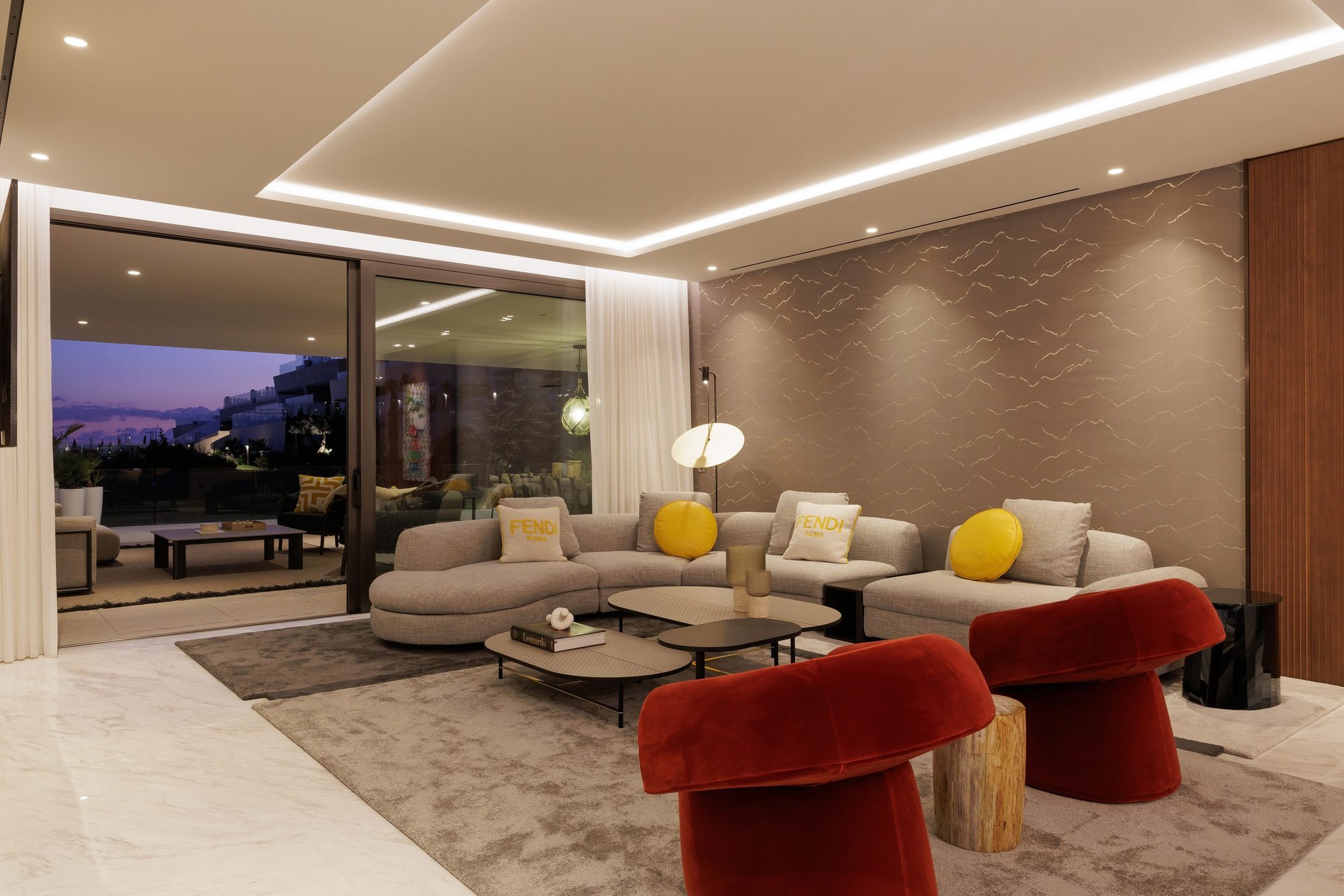 Salón con butacas rojas y ventanal al atardecer — CG Studio Epic Apto II, Costa del Sol. Fotografía de Pedro Jaén