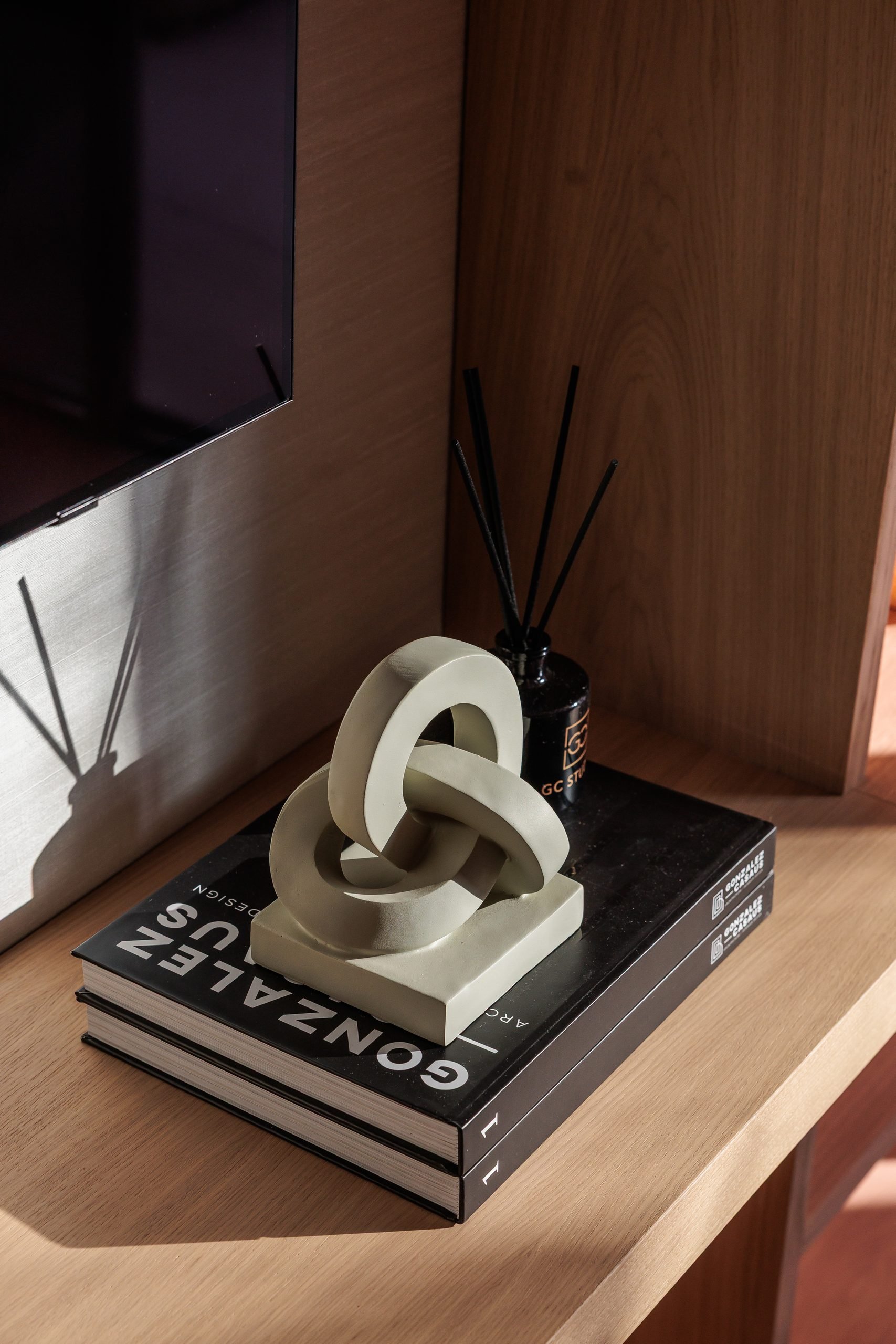 Libros y escultura de eslabones sobre mueble de madera — CG Studio, Costa del Sol. Fotografía de Pedro Jaén