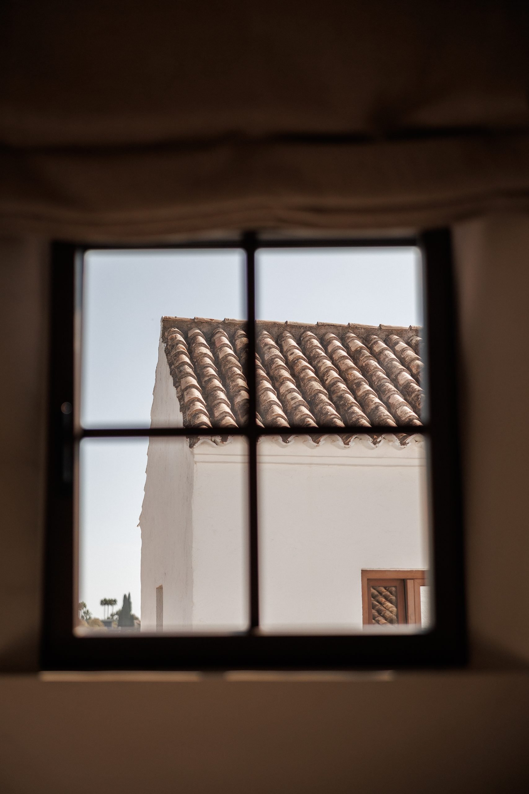 Ventana de madera con vistas a tejado de teja — El Naranjal Archidom, Costa del Sol. Fotografía de Pedro Jaén