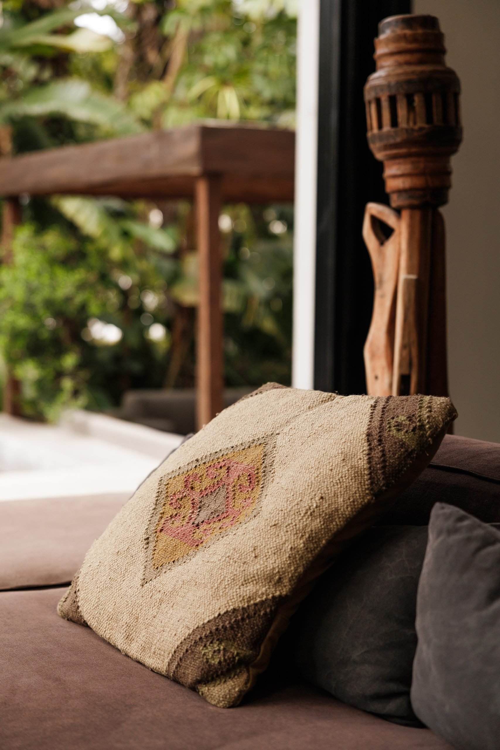 Detalle de cojín bordado y talla de madera junto al ventanal — Endless Grahana Soul Corzo 5, Costa del Sol. Fotografía de Pedro Jaén