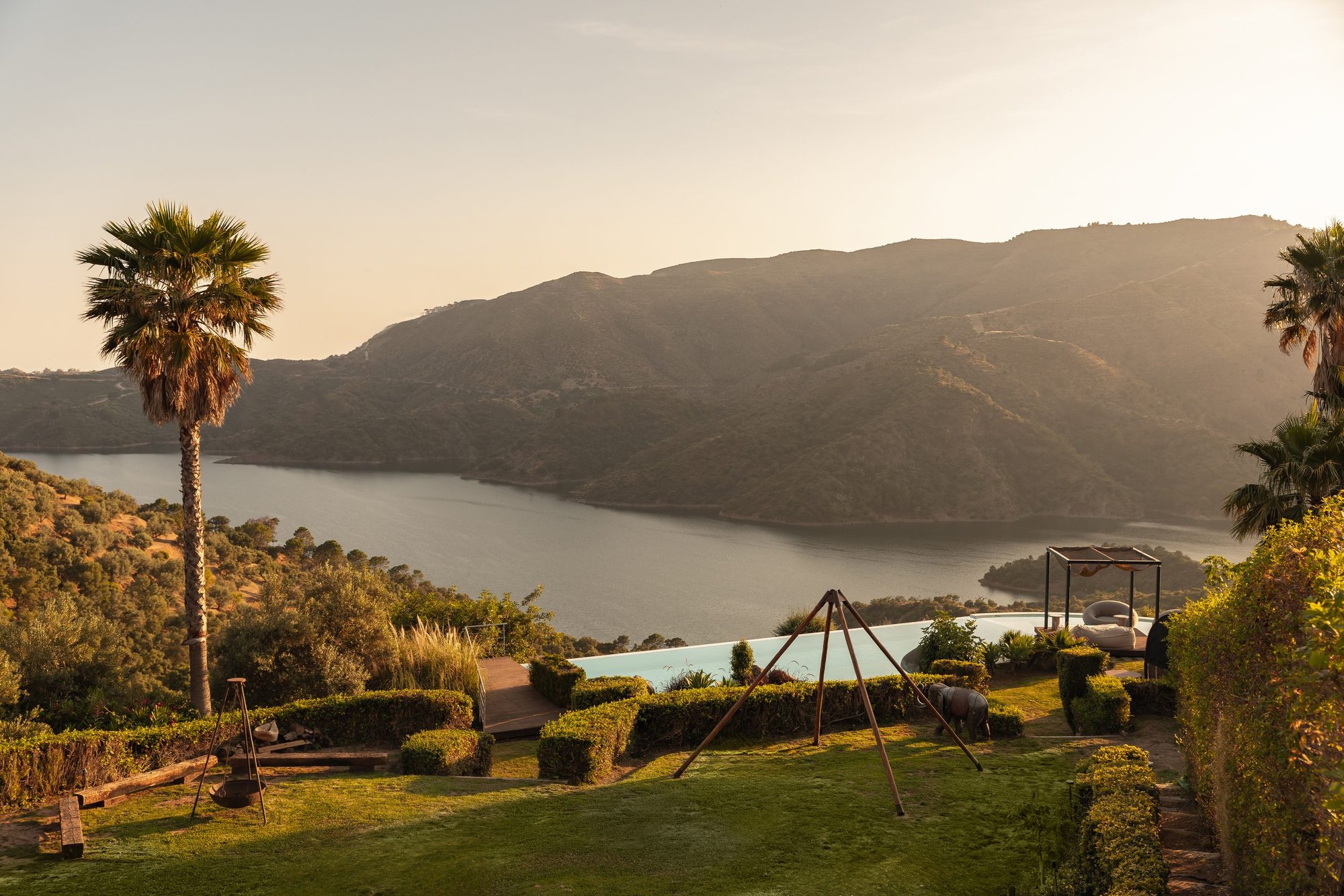 Jardín con palmera y vistas al embalse al atardecer — Endless Istán, Istán, Málaga. Fotografía de Pedro Jaén