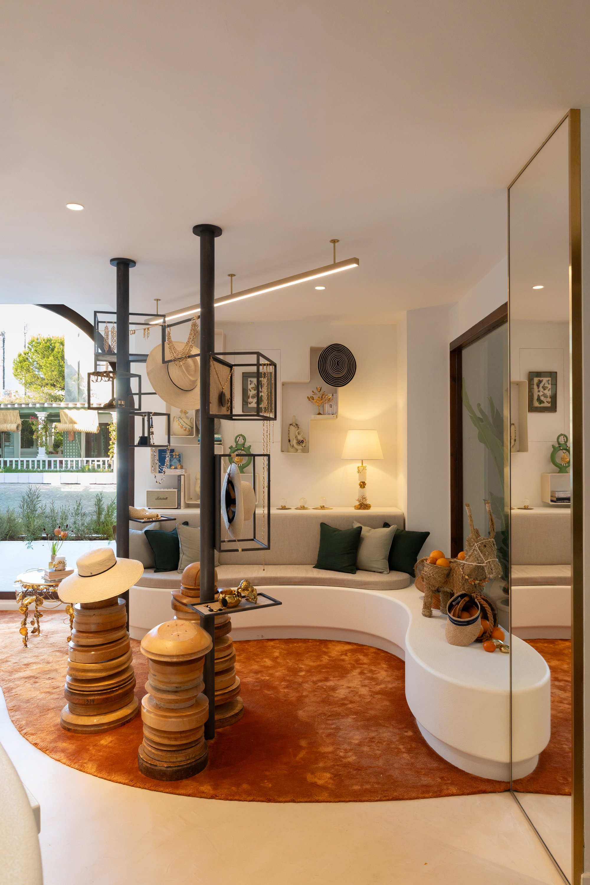 Salón de la boutique con pilares de sombreros y alfombra naranja — Maison Michel + Goossens, Marbella Club Hotel, Marbella. Fotografía de Pedro Jaén
