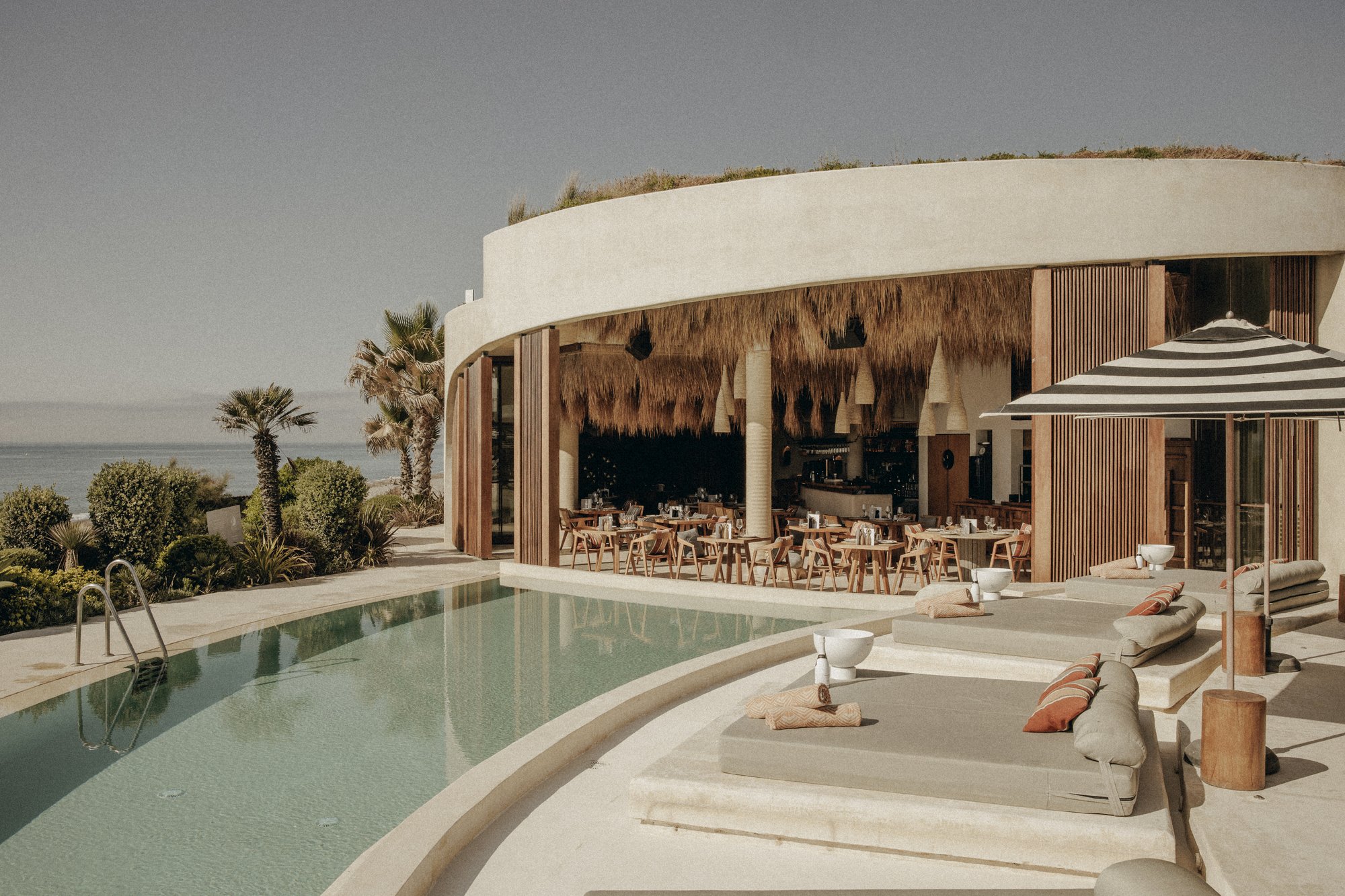 Edificio circular con piscina y sombrillas de rayas — Nido, Marbella. Fotografía de Pedro Jaén