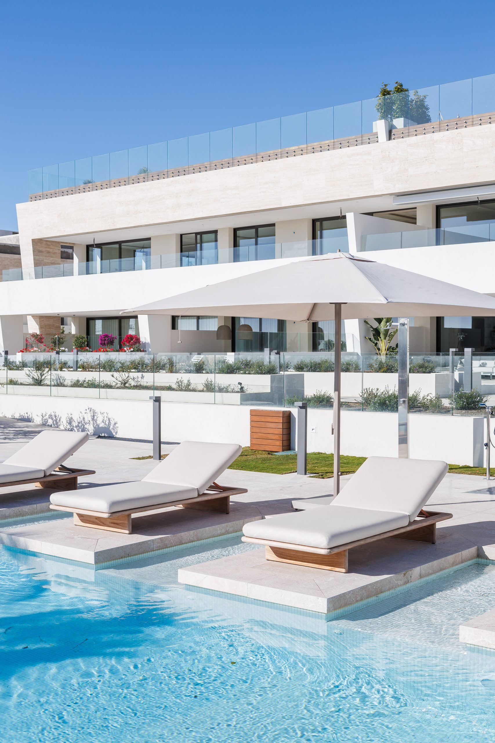 Fachada blanca escalonada sobre la piscina con tumbonas — Sierra Blanca Epic, Sierra Blanca, Marbella. Fotografía de Pedro Jaén