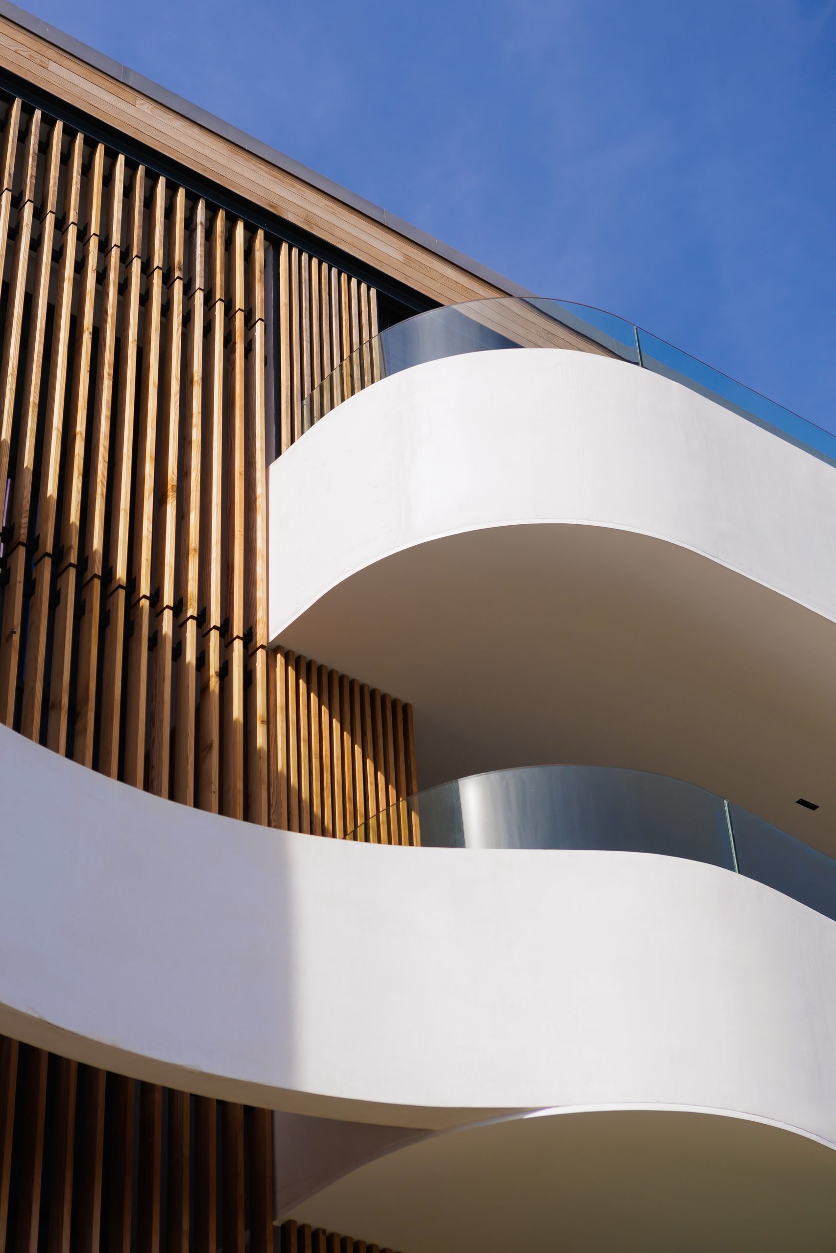 Terrazas curvas blancas y listones de madera — Sotogrande Village Verde, Sotogrande, Cádiz. Fotografía de Pedro Jaén