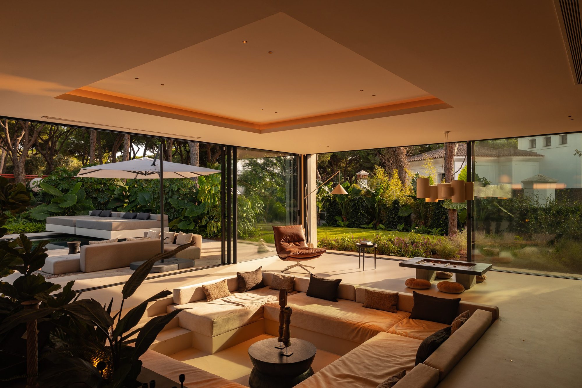 Salón hundido abierto al jardín con grandes ventanales — Villa Copal, Cabopino, Marbella. Fotografía de Pedro Jaén